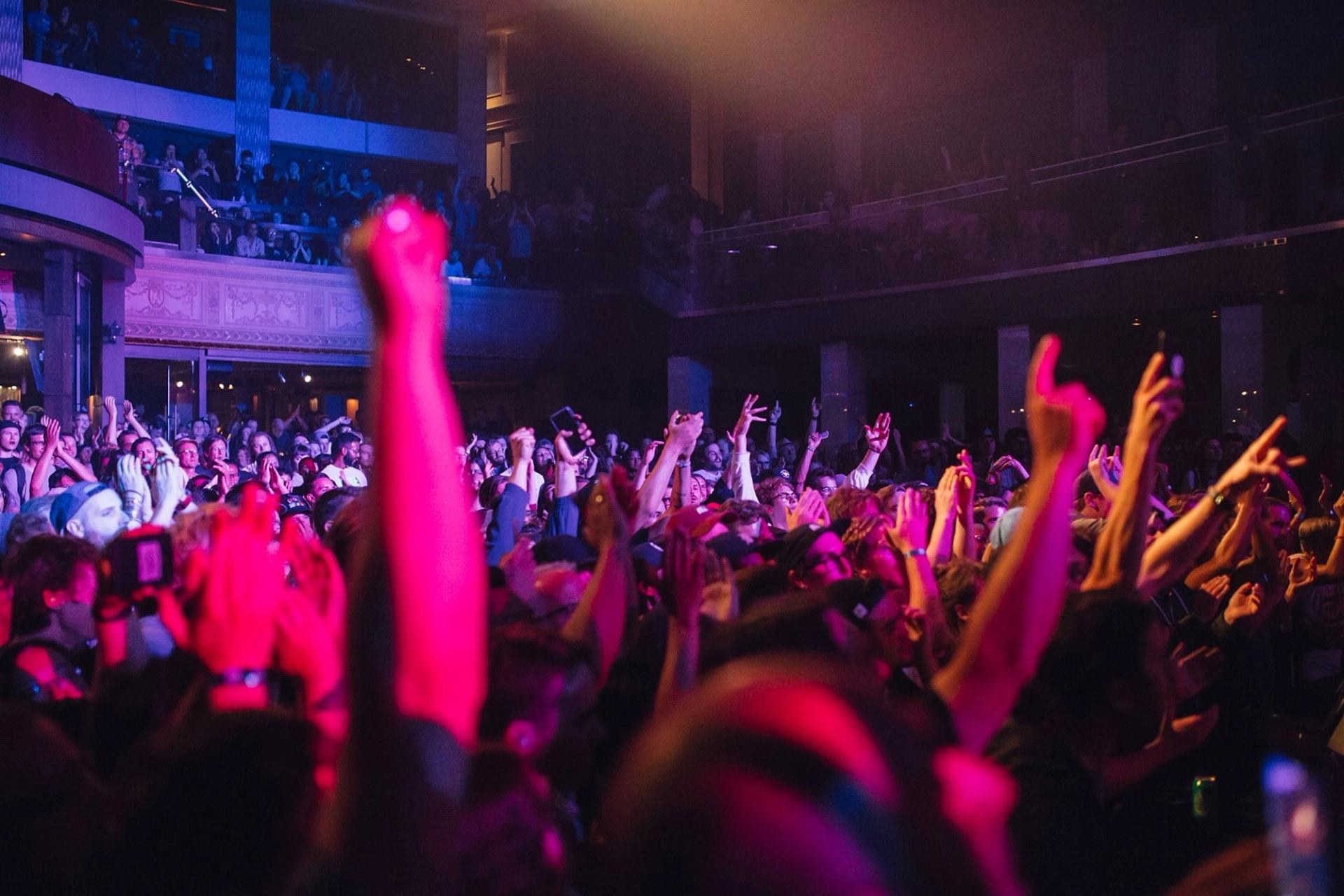 A crowded indoor concert with raised arms and colorful lighting at Sled Island Music & Arts Festival.