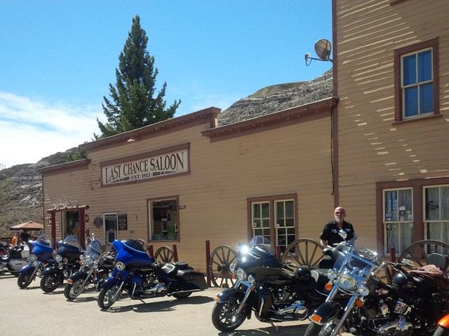 Harley-Davidsons parked outside rustic building under clear skies.