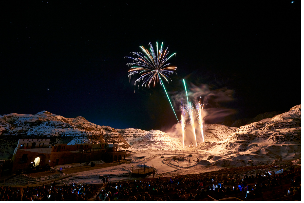 Green fireworks explode above the hills of the Badlands Amphitheatre