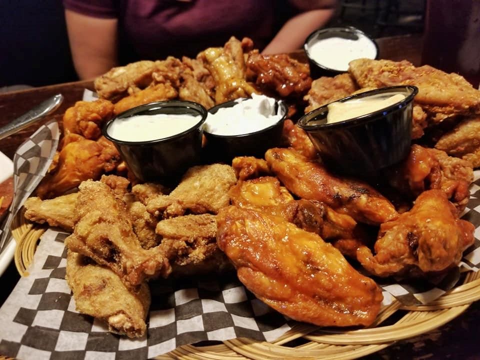 A platter of chicken wings with dipping sauces.