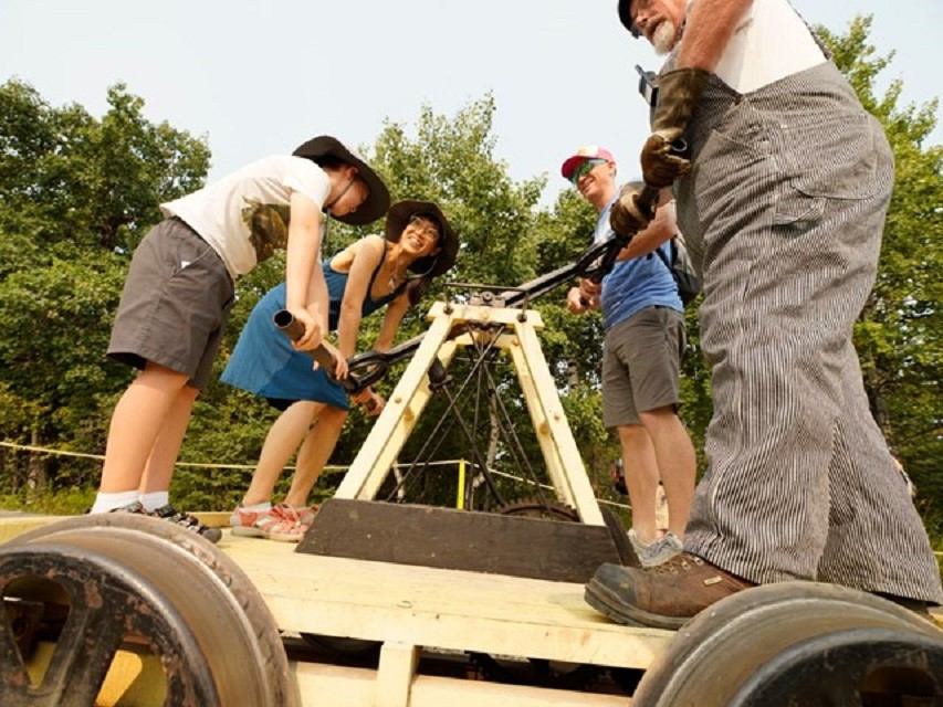 Four people operate a handcar on tracks at Heritage Park.