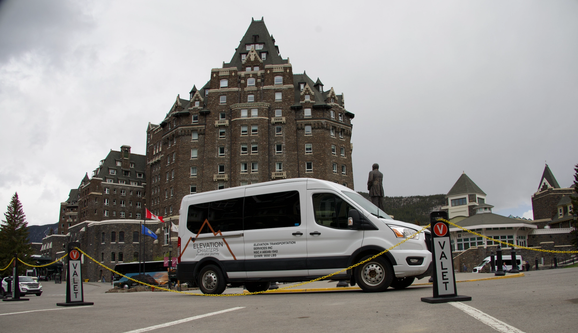 White Elevation Charters van parked at hotel valet area in front of stone building.