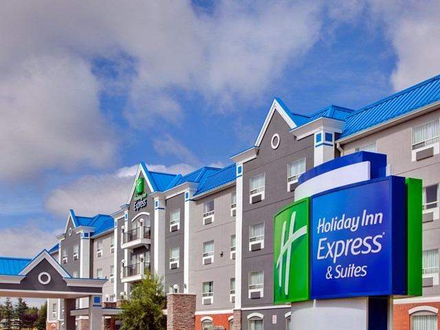 Exterior of Holiday Inn Express Calgary South with hotel sign, gray facade, and blue roof accents.
