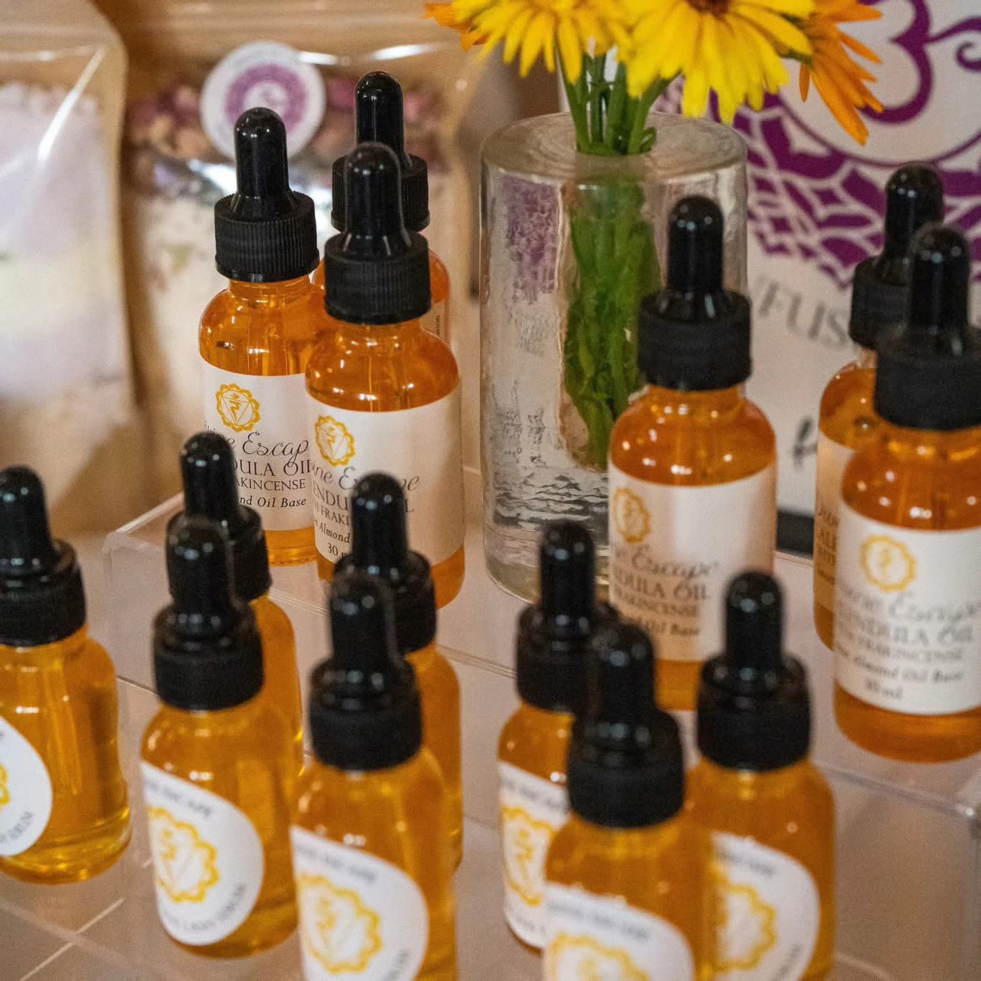 Amber dropper bottles with white labels displayed beside yellow flowers.