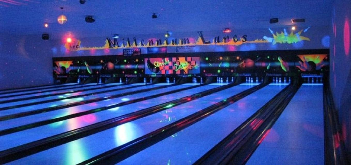 Bowling lanes at Millennium Lanes with overhead lights and decorative wall screens.