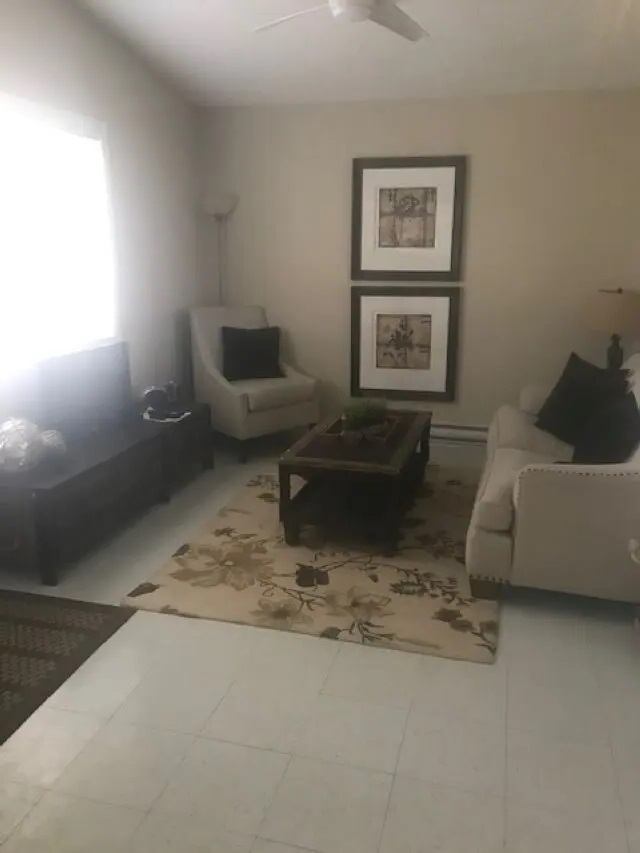 Living room with beige sofa, armchair, coffee table and floral area rug.