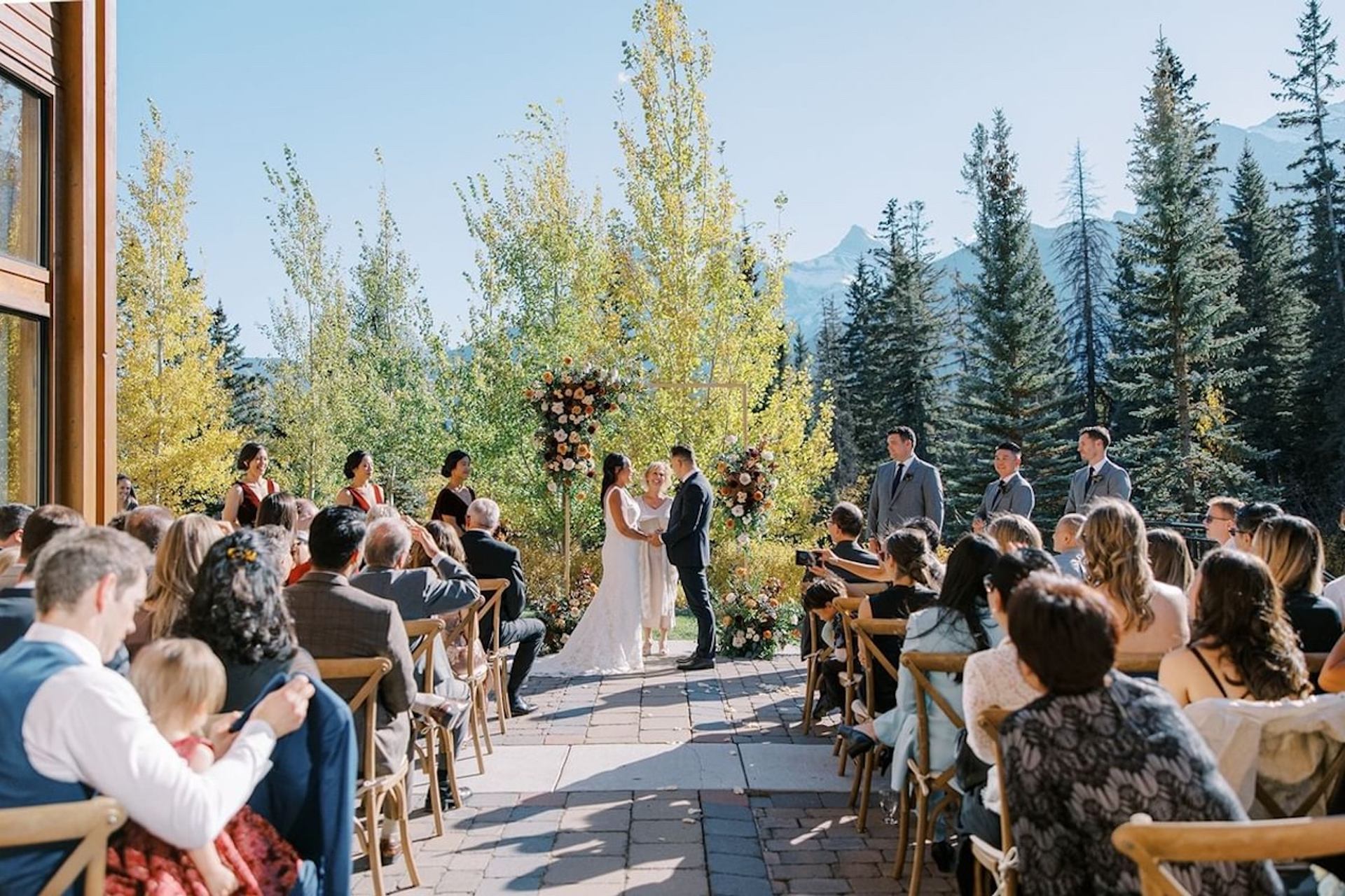 Outdoor wedding ceremony with chairs set before trees and mountain peaks