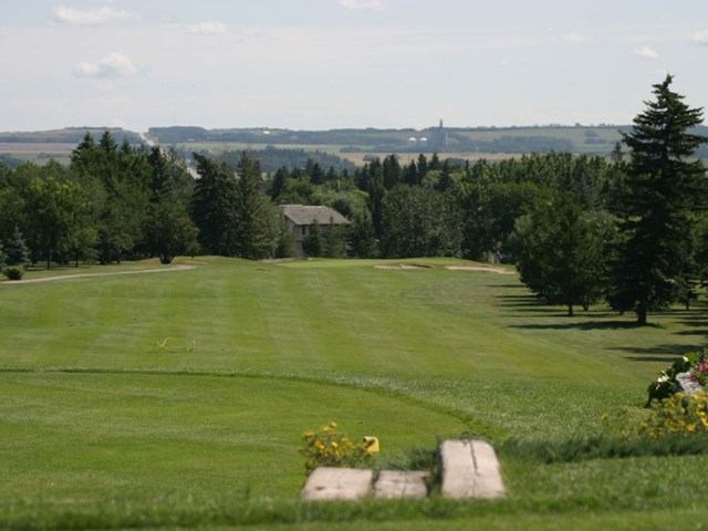 Wide fairway view with trees and distant hills at Lacombe Golf and Country Club.
