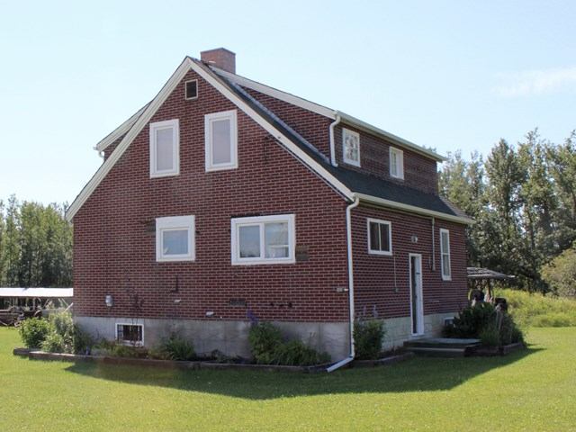 A red brick house surrounded by a spacious yard, showcasing a well-maintained outdoor area.