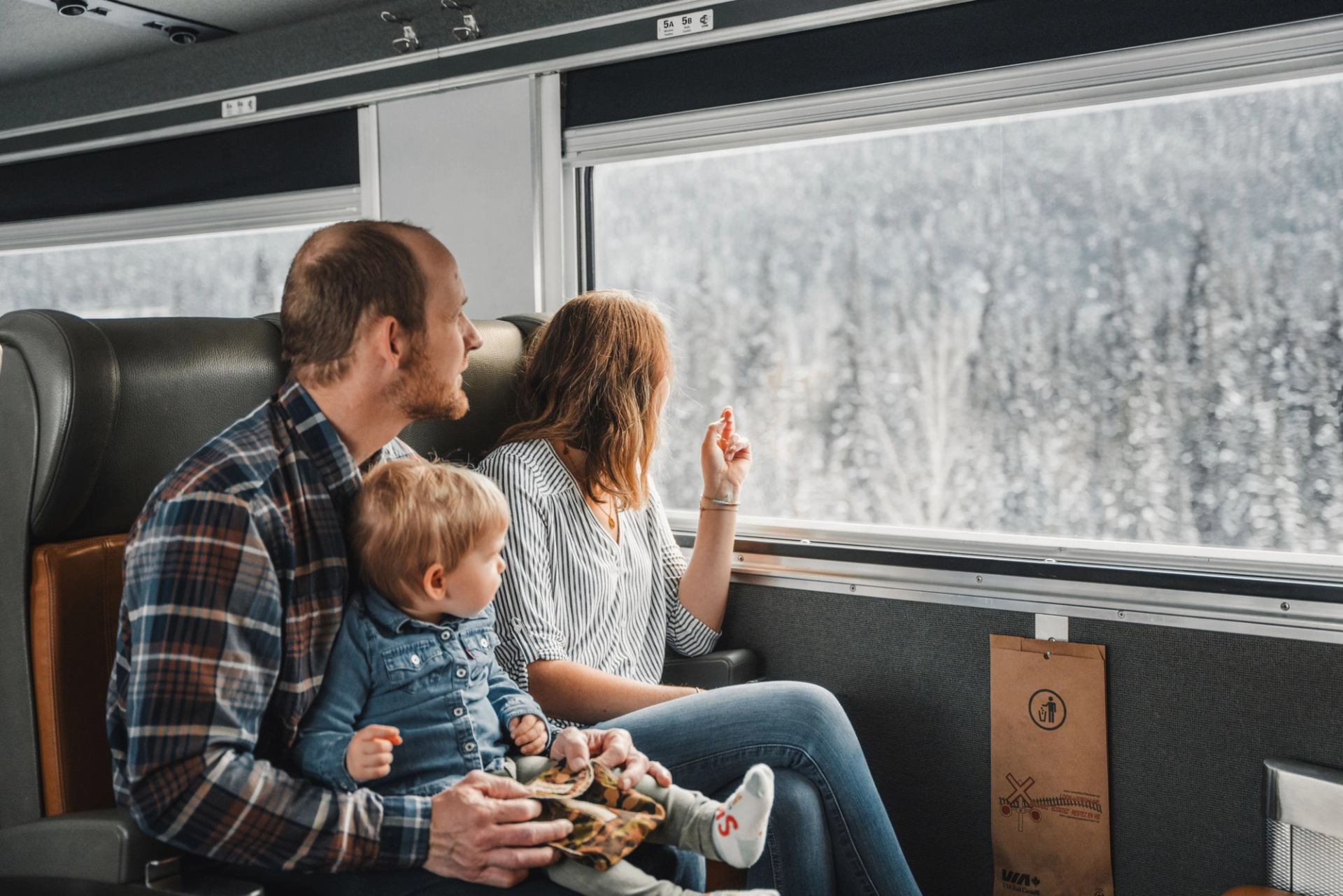 A family on a train looks out a window at a snowy landscape.