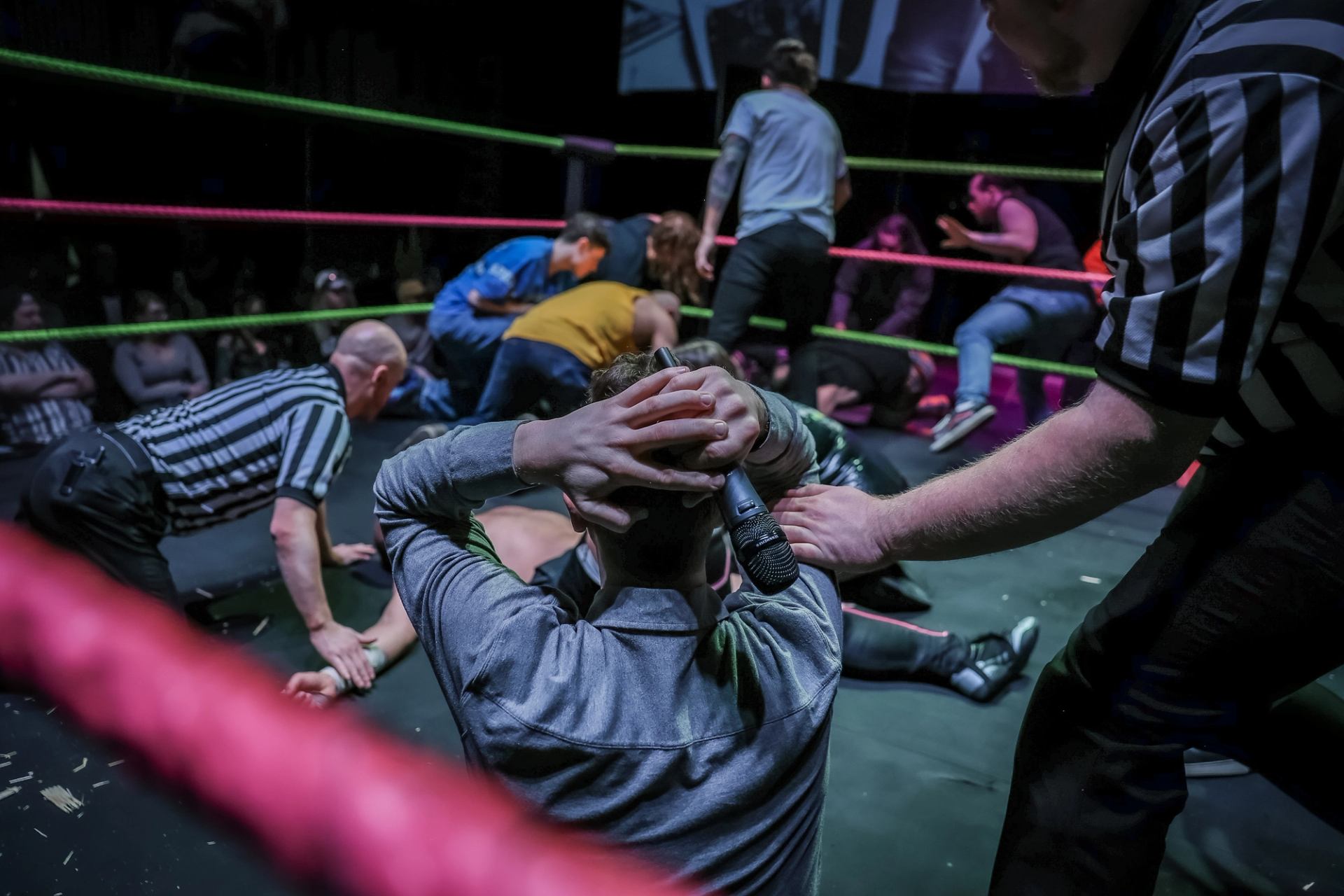 Multiple wrestlers and referee inside ring during chaotic multi person fight scene.