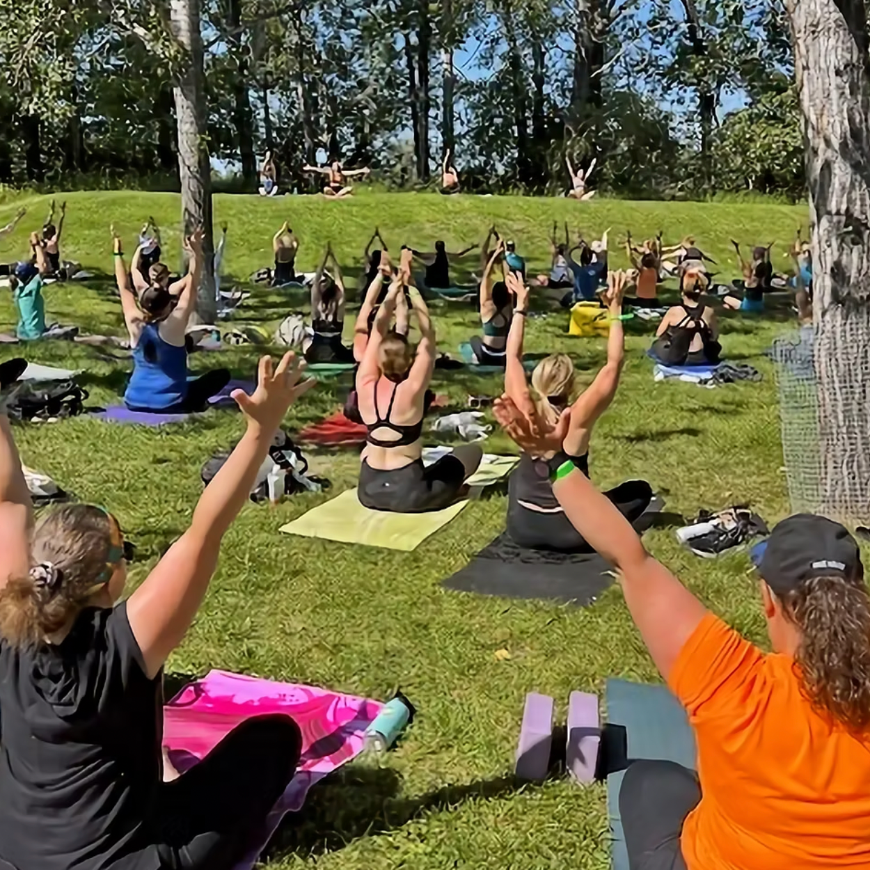 A group of women sitting on mats outside doing Yoga