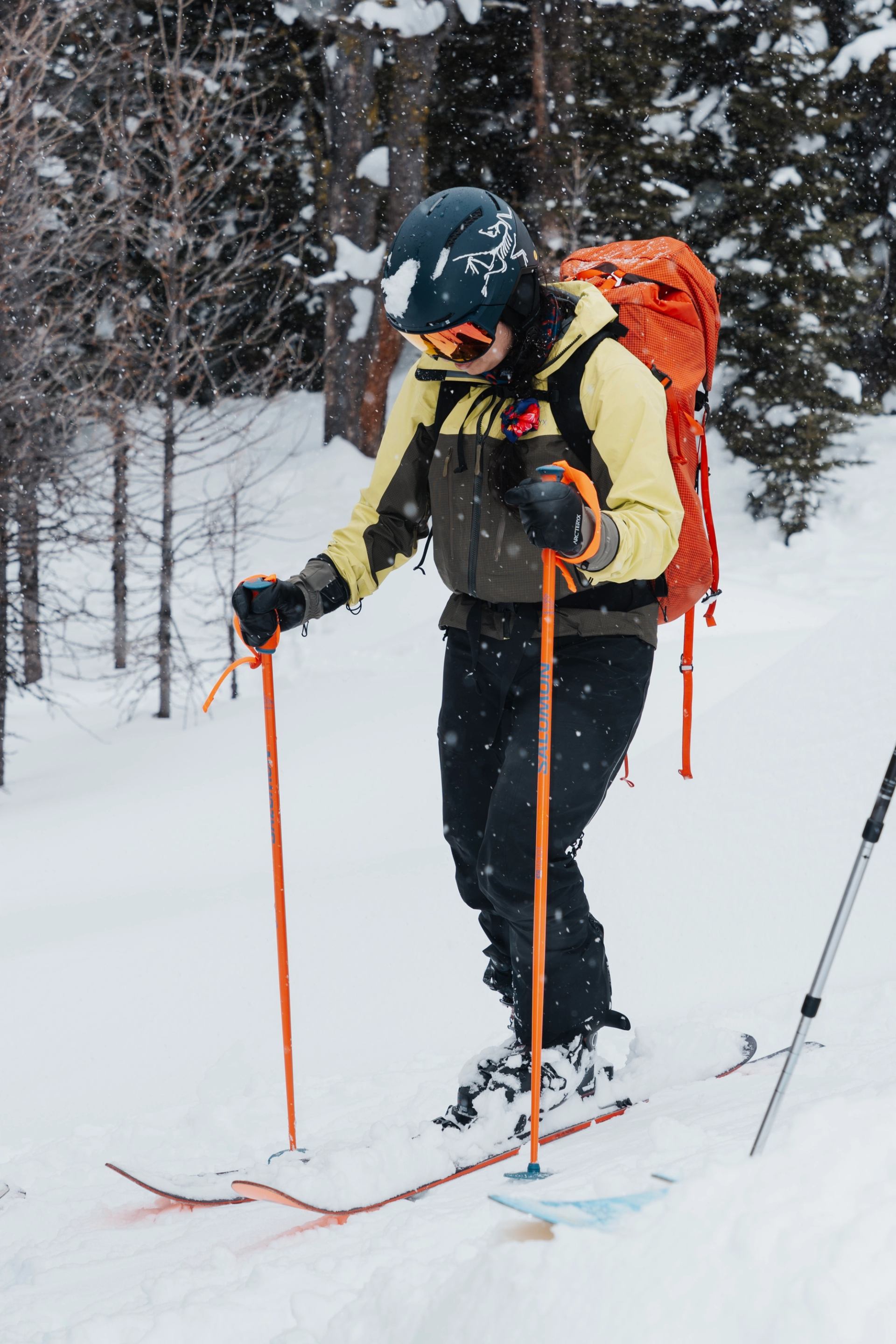 A skier with a backpack practices technique on a snowy trail during a winter lesson.
