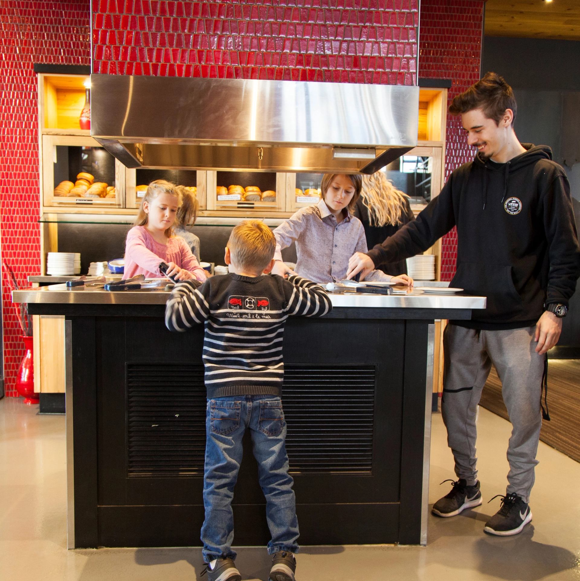 Kids and adult toasting bread at all you can eat bread bar in a restaurant setting.