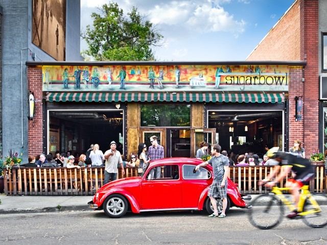 xterior view of Sugarbowl with outdoor seating and a red vintage car parked