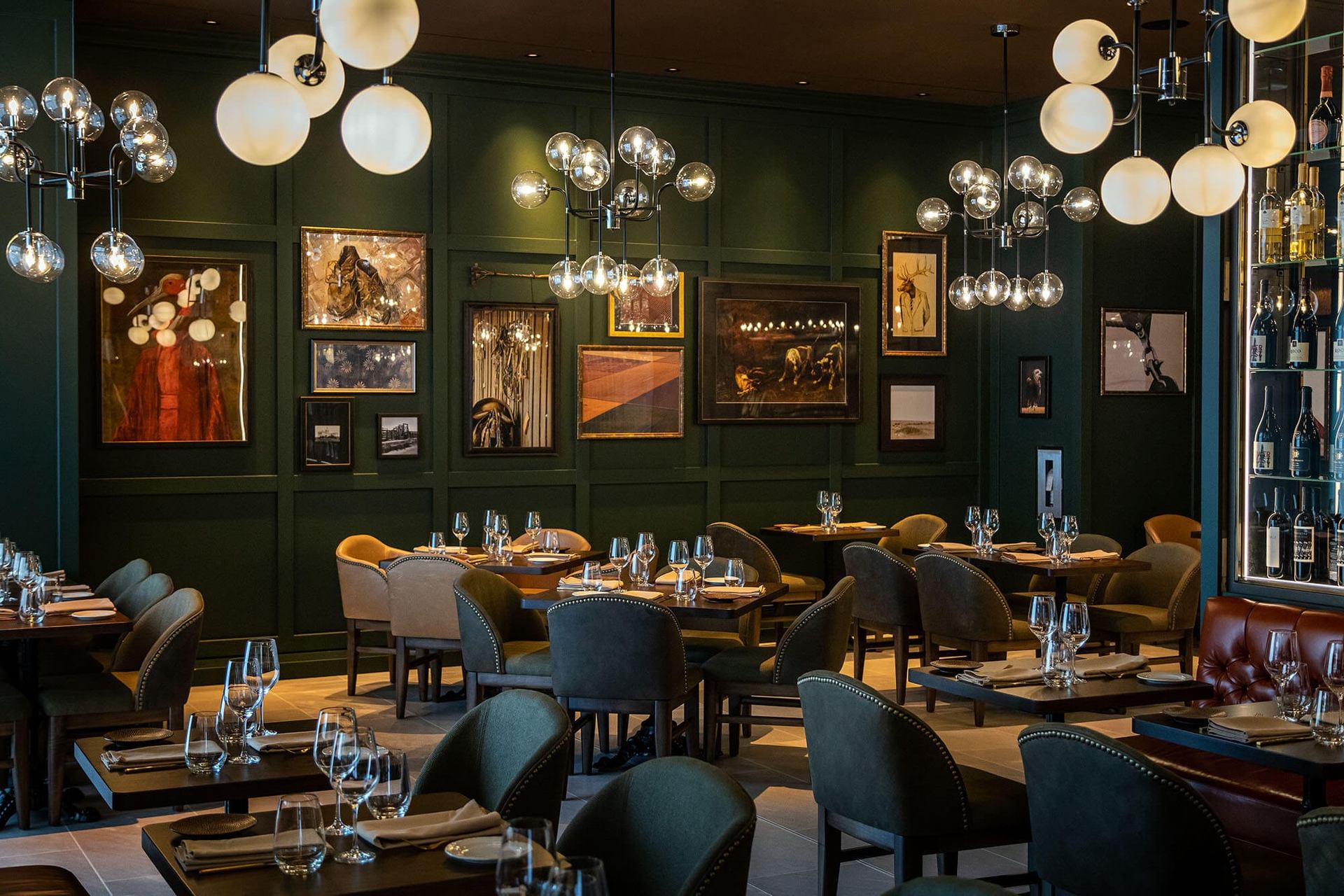 Upscale dining room with modern chandeliers, framed art, and set tables