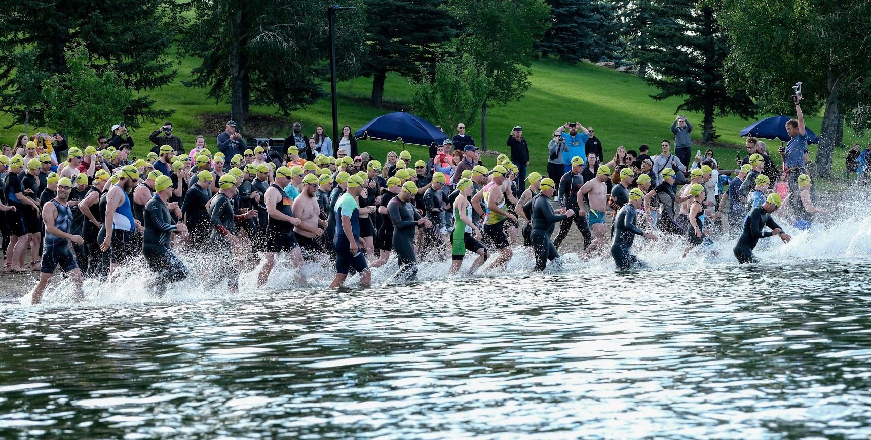 Athletes in wetsuits and green swim caps start the swim portion of the Lake Chaparral Triathlon.
