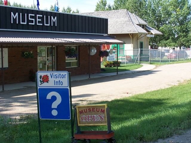 Museum building with MUSEUM sign, Visitor Info question-mark sign, and Museum Open sign.