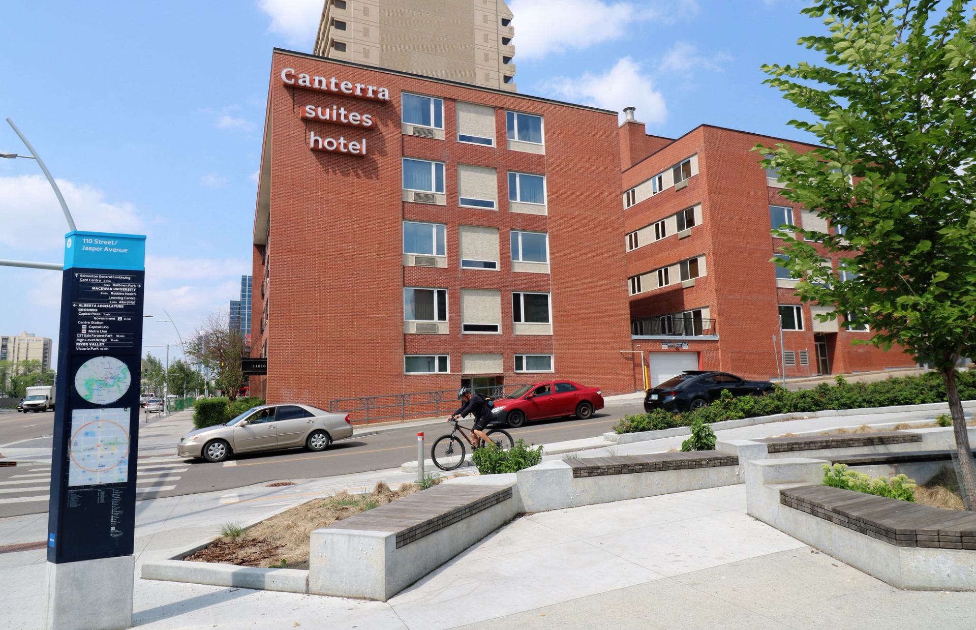 Canterra Suites Hotel with red brick exterior at 110 St and Jasper Ave, near cars and city signage.