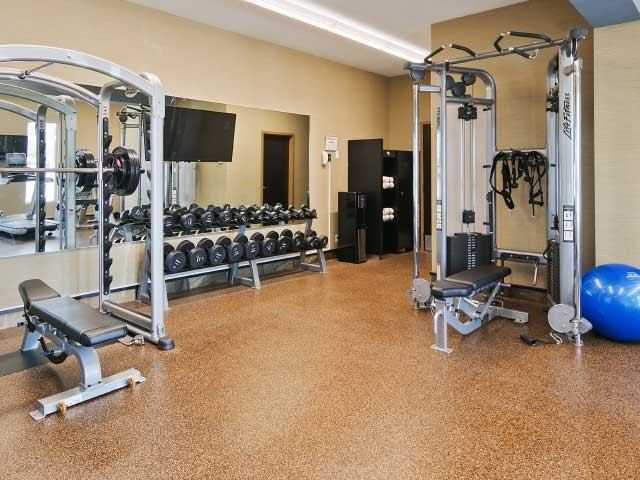 Gym room with weight machines, free weights, a mirror wall, and exercise equipment.