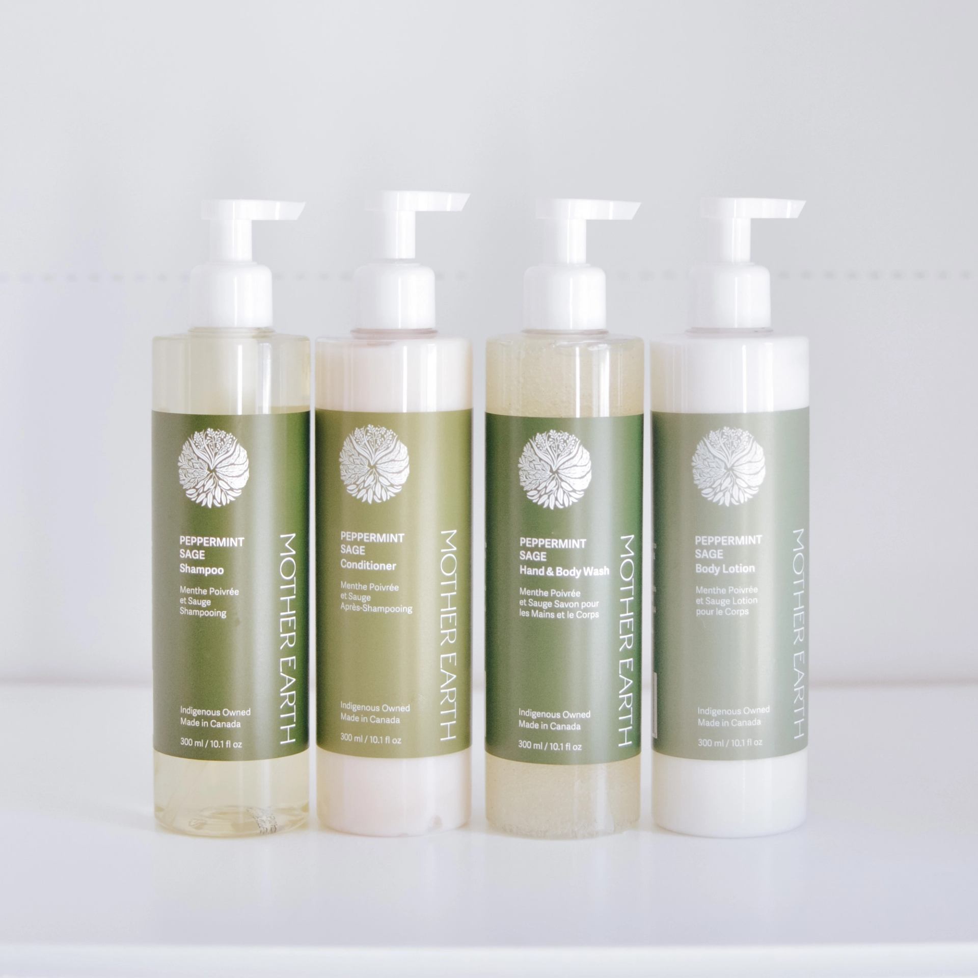 Four Mother Earth peppermint sage bottles with pump tops on a white surface.
