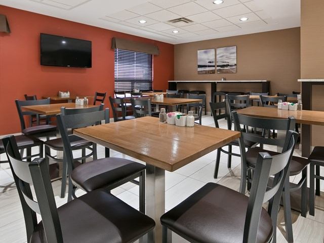 Dining room with wooden tables, chairs, and TV at Best Western Plus Red Deer.