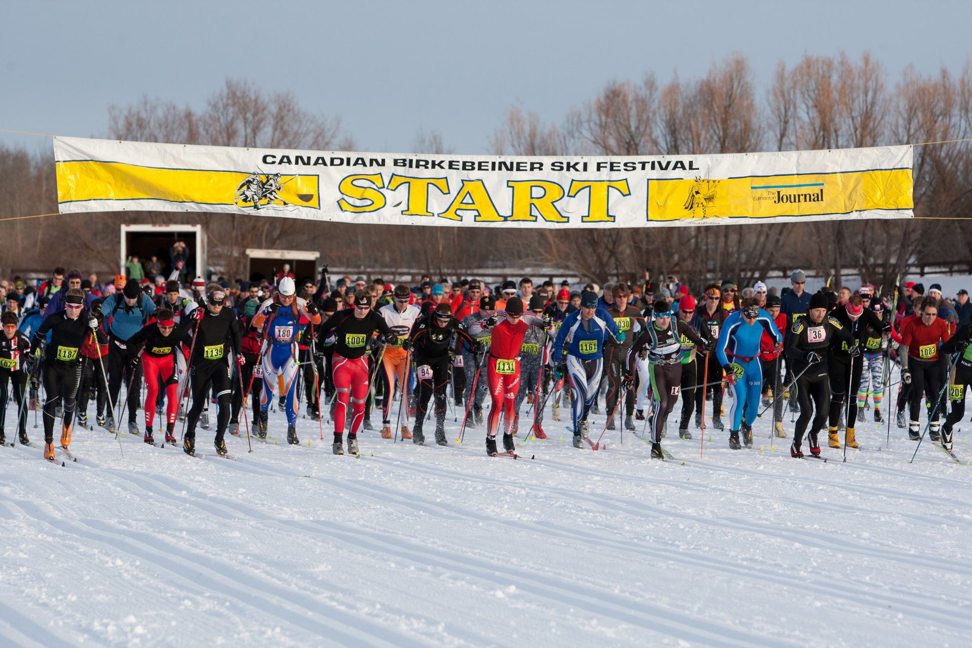 Cross-country skiers line up under Canadian Birkie Ski Festival banner at race start.