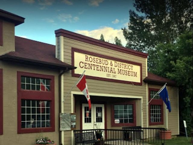 Front entrance with flags, historical sign and flowers.