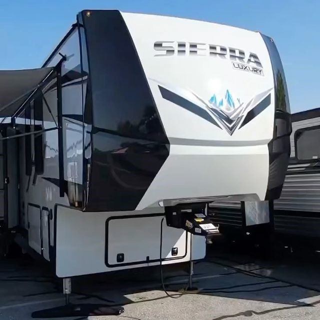 Sierra RV with extended awning in black and white parked outdoors.