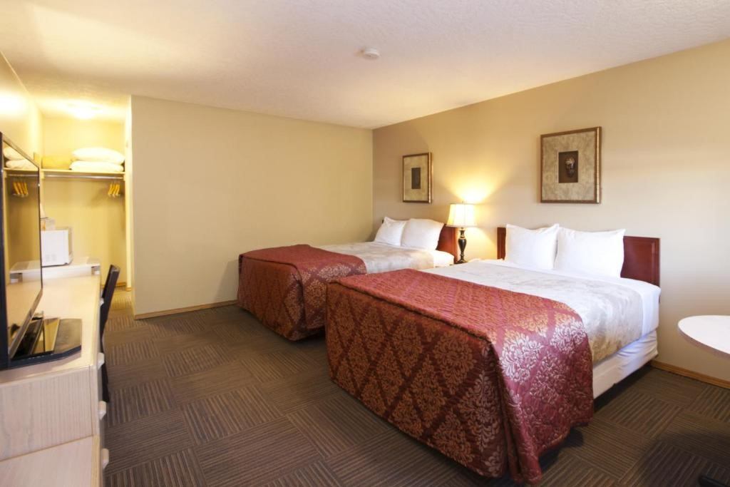 Bow River Inn guest room with two queen beds, warm lighting, and an open closet area.