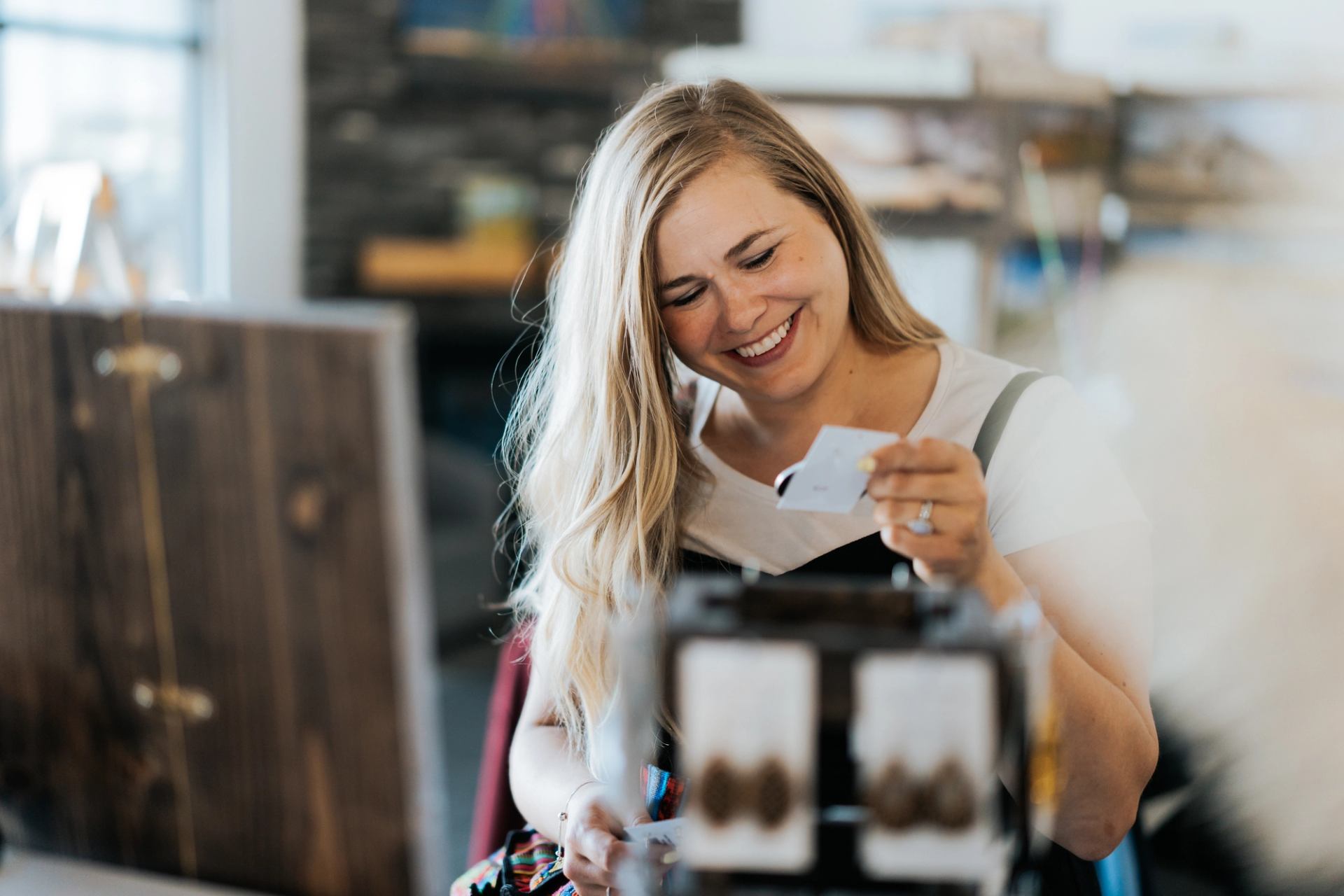 A person looking at items in a boutique shop while holding a small card.