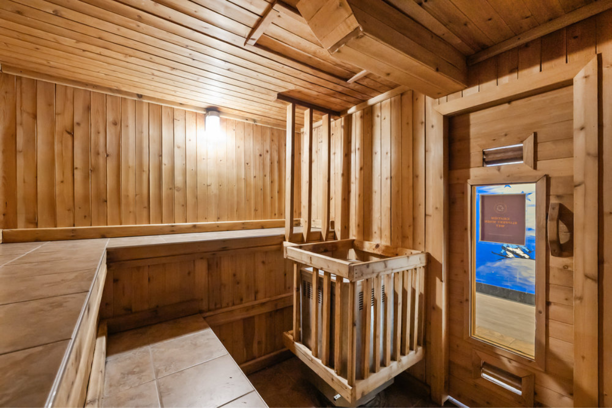 Sauna with wooden benches, traditional bucket and ladle, and warm cedar walls.