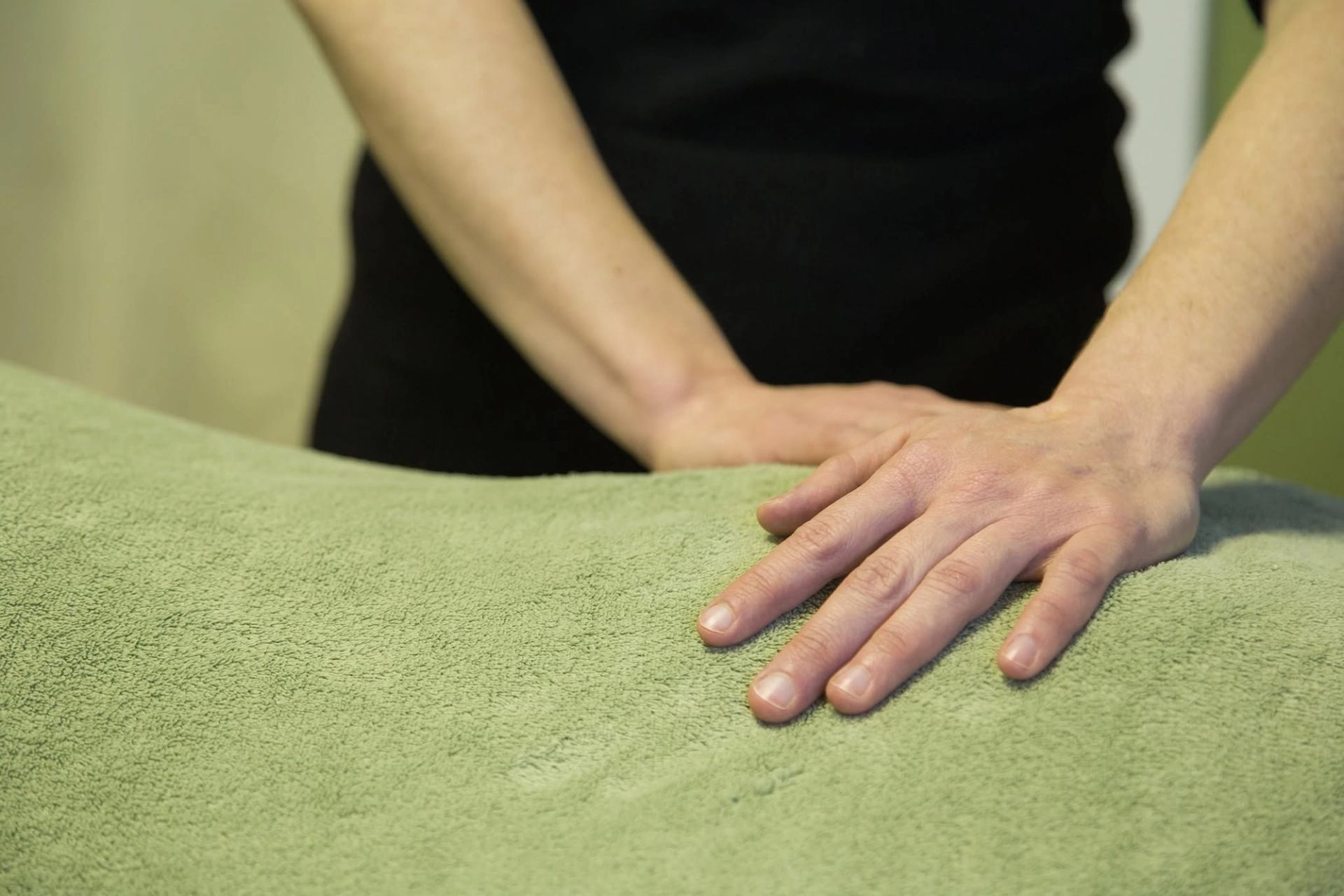A massage therapist applies pressure during a therapeutic treatment on a comfortably covered massage table.
