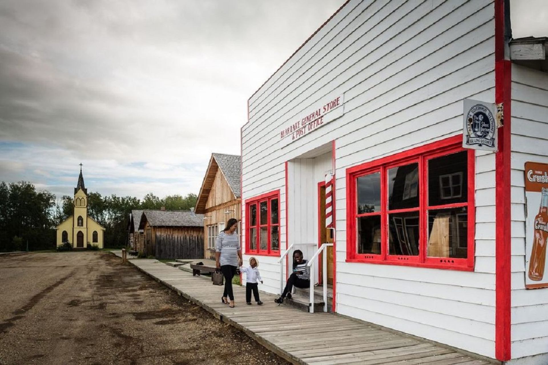 Historic white general store and nearby buildings along a boardwalk in Pioneer Village.