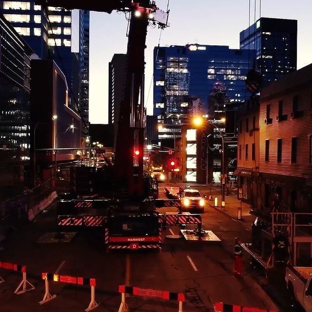 Downtown street with construction crane, barriers, traffic lights and high-rise buildings.