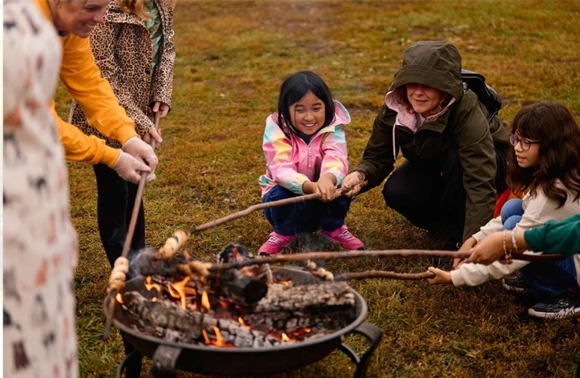 Children and adults roast food over an open fire