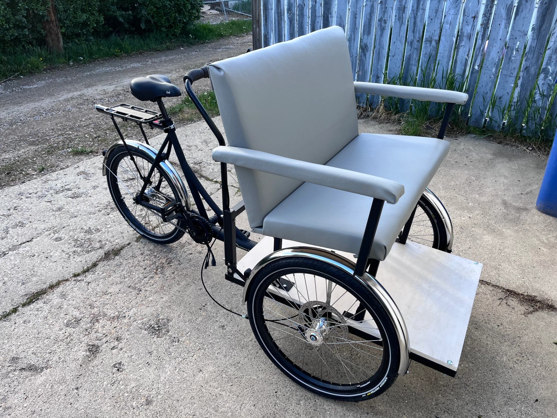 Three-wheeled cycle with a large grey passenger seat and front footrest.