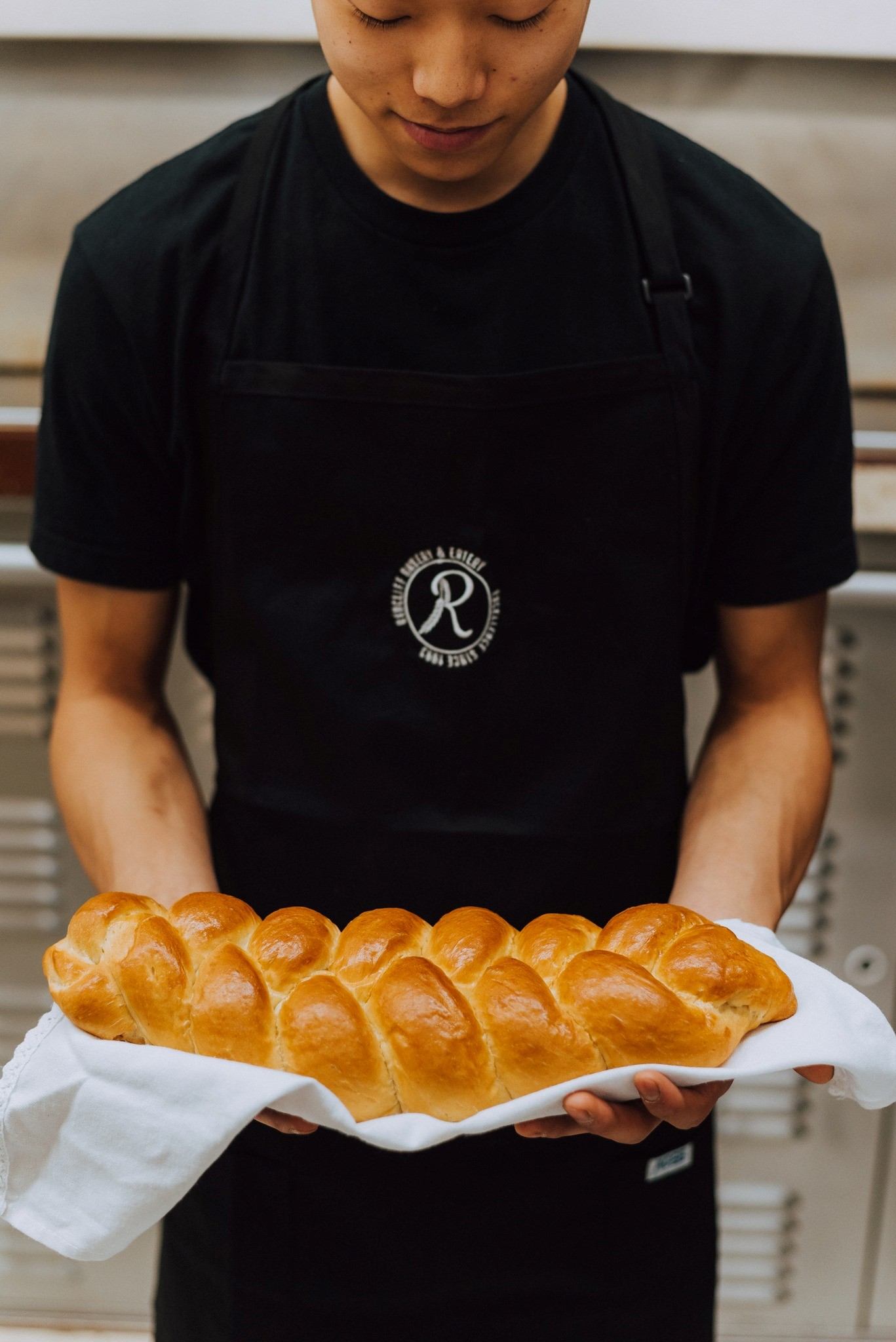 Person holding a fresh braided loaf from Redcliff Bakery.