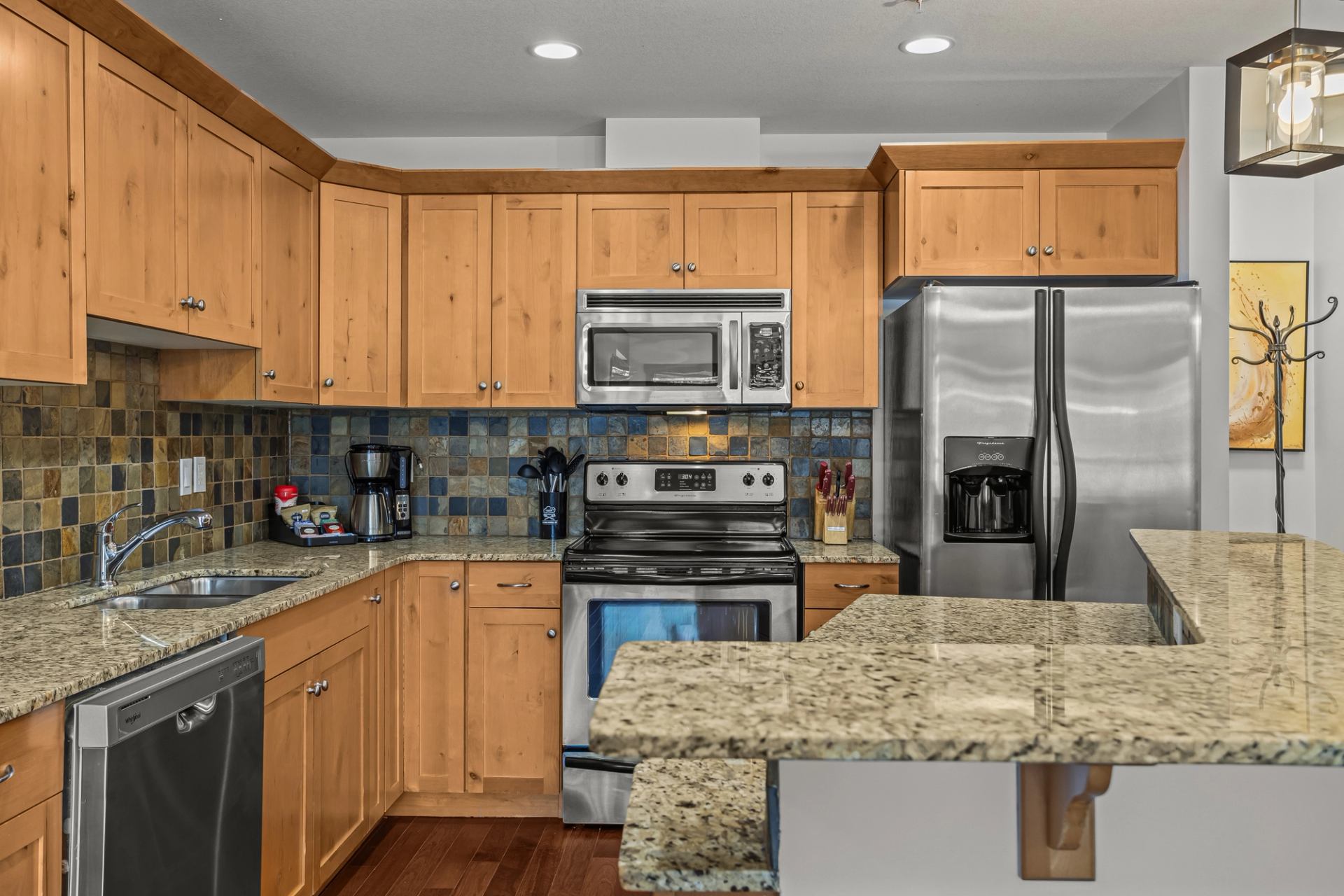 Kitchen with wood cabinets, granite counters, stainless appliances and tiled backsplash.