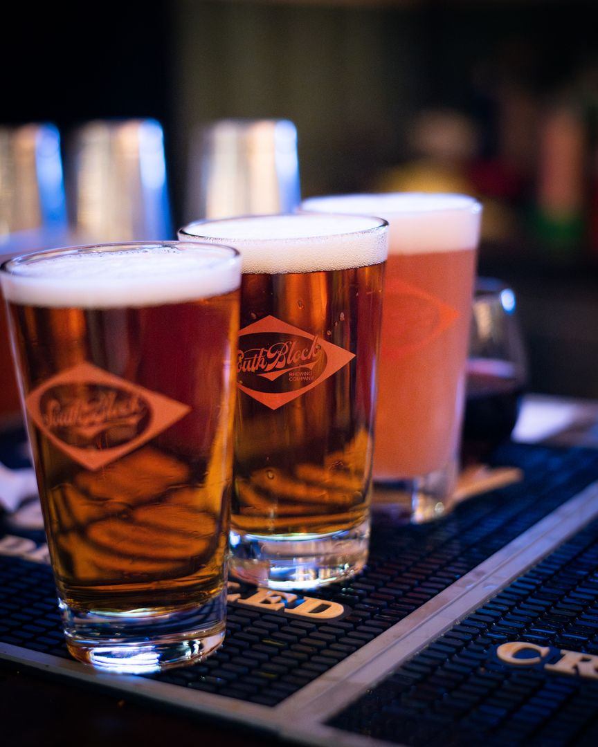 Three glasses of craft beer lined up on a bar mat.