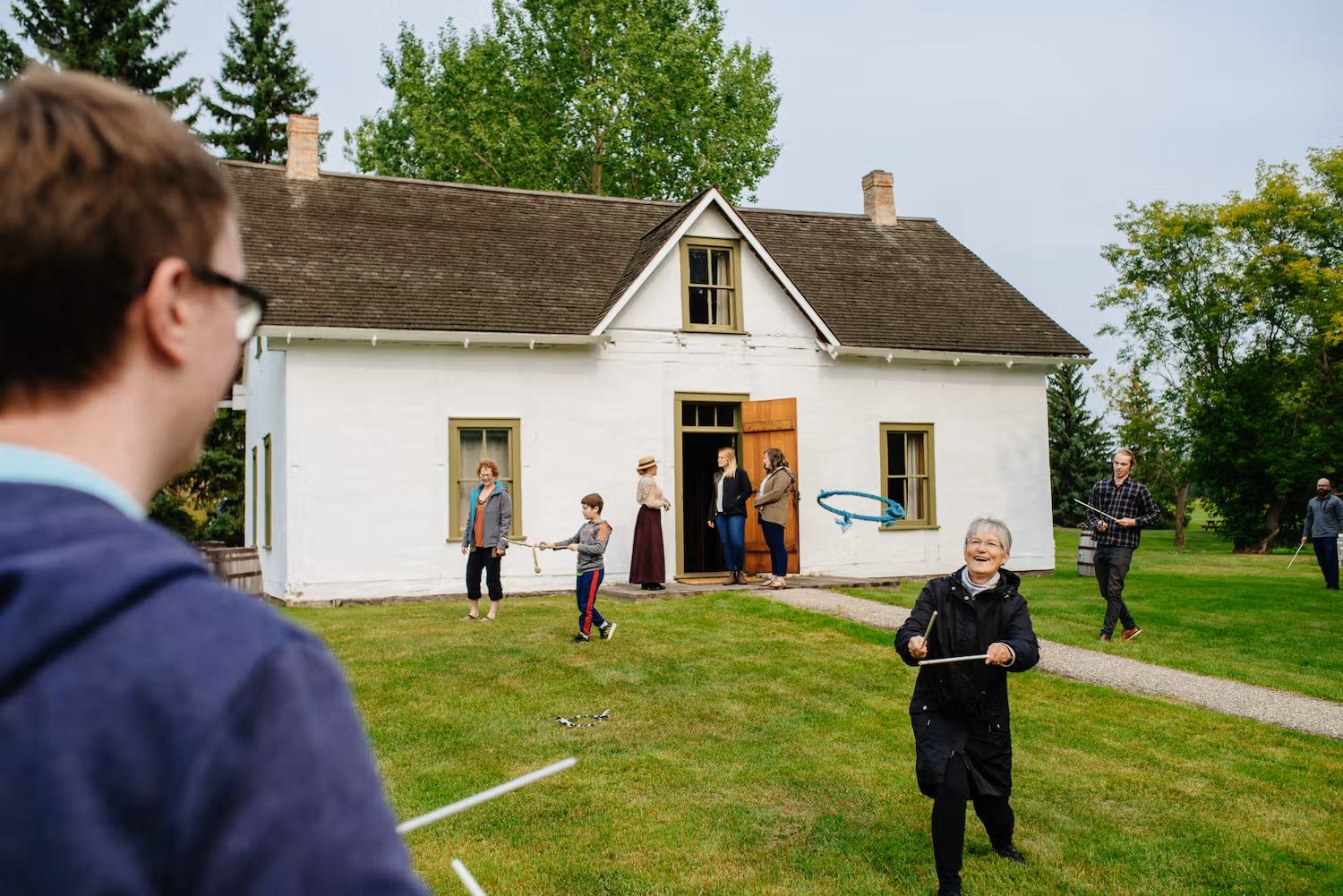 People playing outdoor games on the grass in front of a white historic house.
