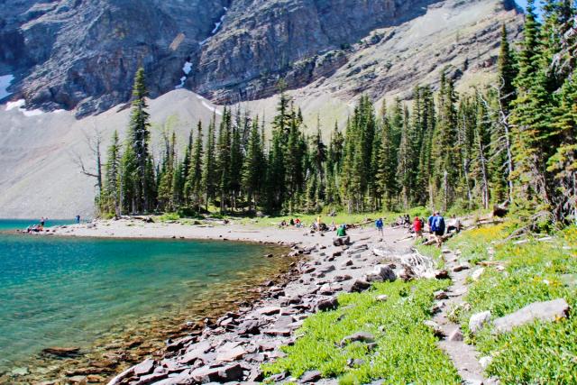 Wide shot of backpackers hiking along the lake.