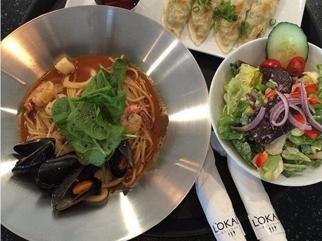 Seafood pasta with mussels, salad and dumplings beside Lokal napkins.