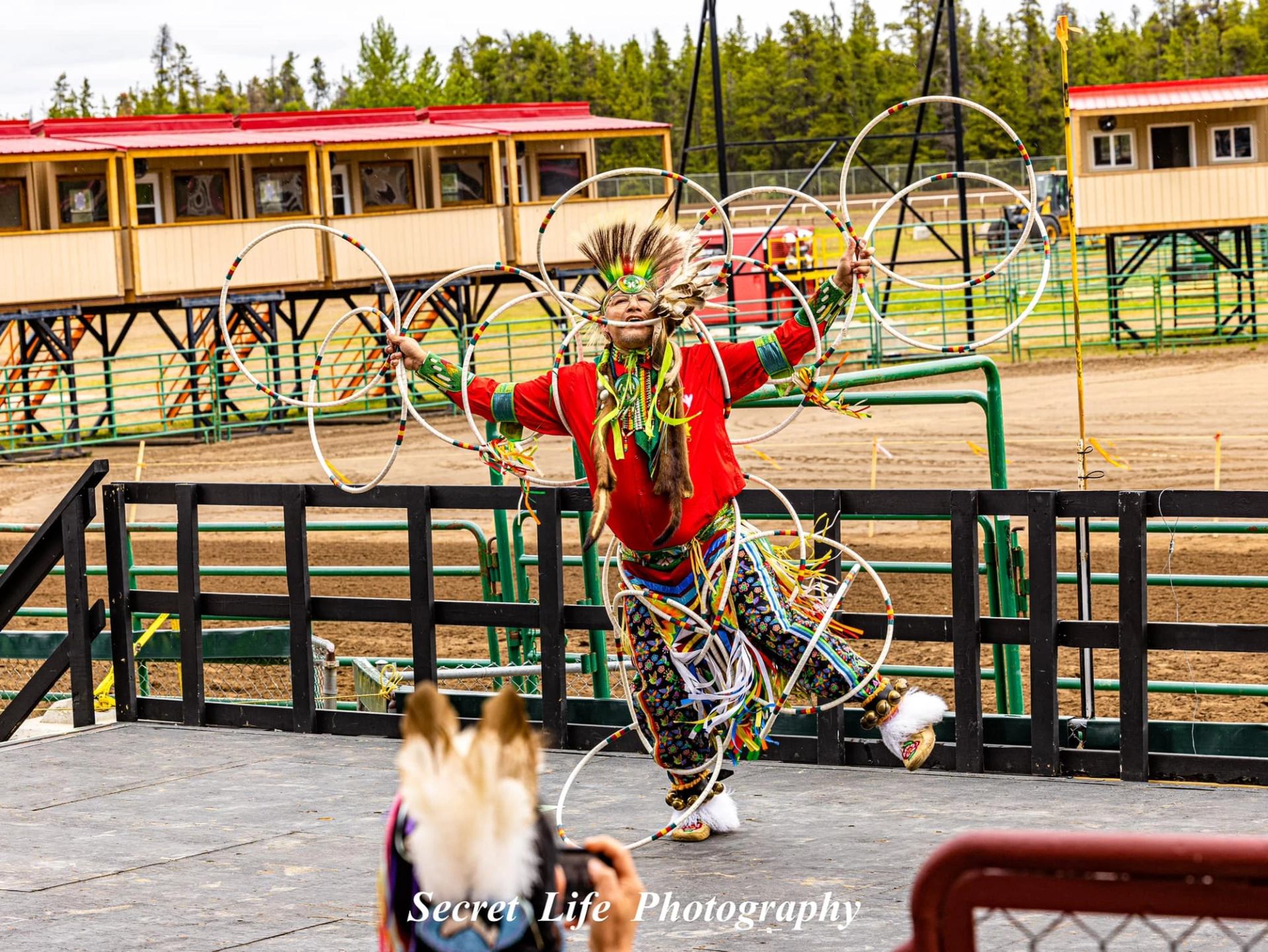 Performer dancing with multiple hoops on an outdoor stage.