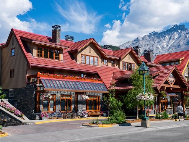 Banff Ptarmigan Inn with red roof, flower planters, and mountain backdrop.