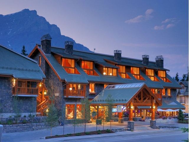 Lodge-style Fox Hotel with warm lights and mountain backdrop at twilight.