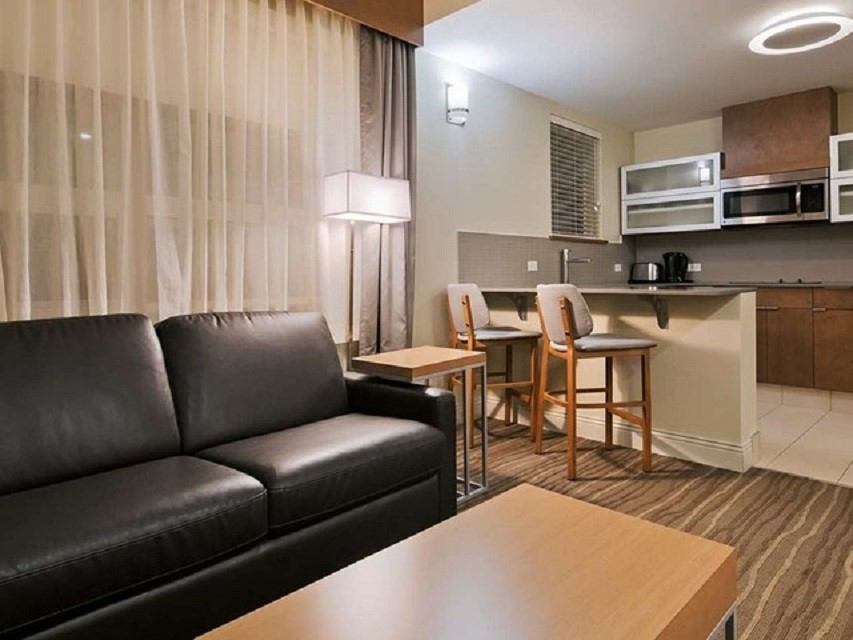 Modern suite with leather sofa, dining area, and full kitchen at Best Western Plus.
