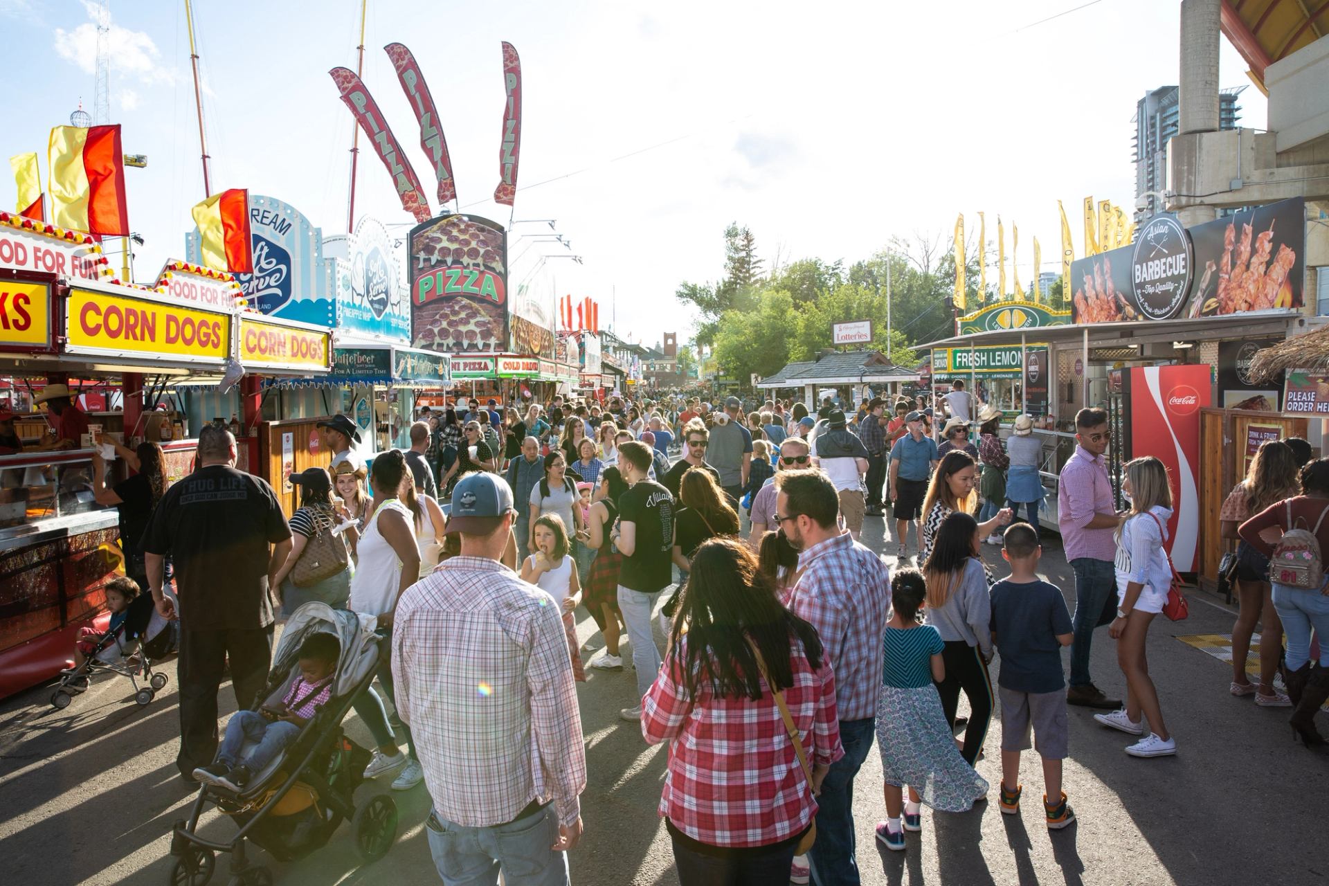 Crowded fairground with food stalls and visitors.