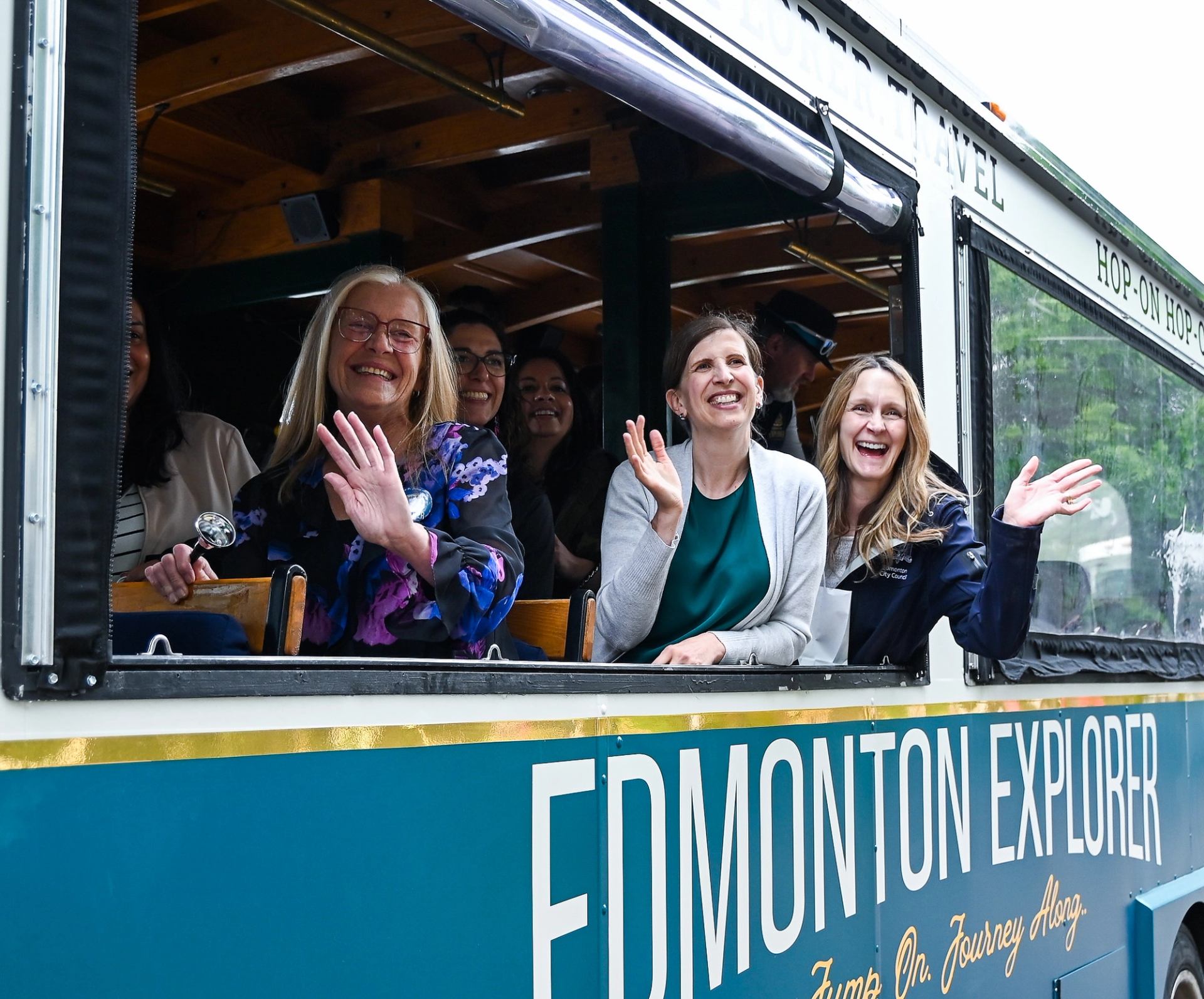 A group of happy people waving from on board the Edmonton Explorer