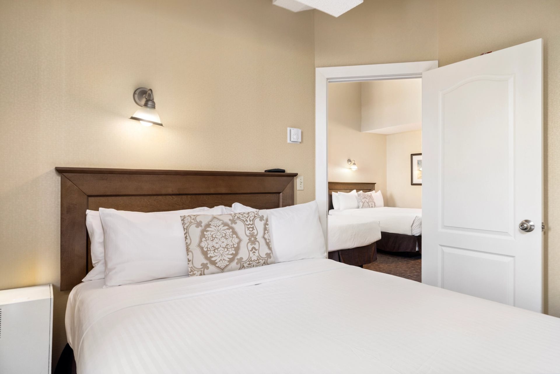 Hotel suite with two beds, warm lighting, and connecting room layout.
